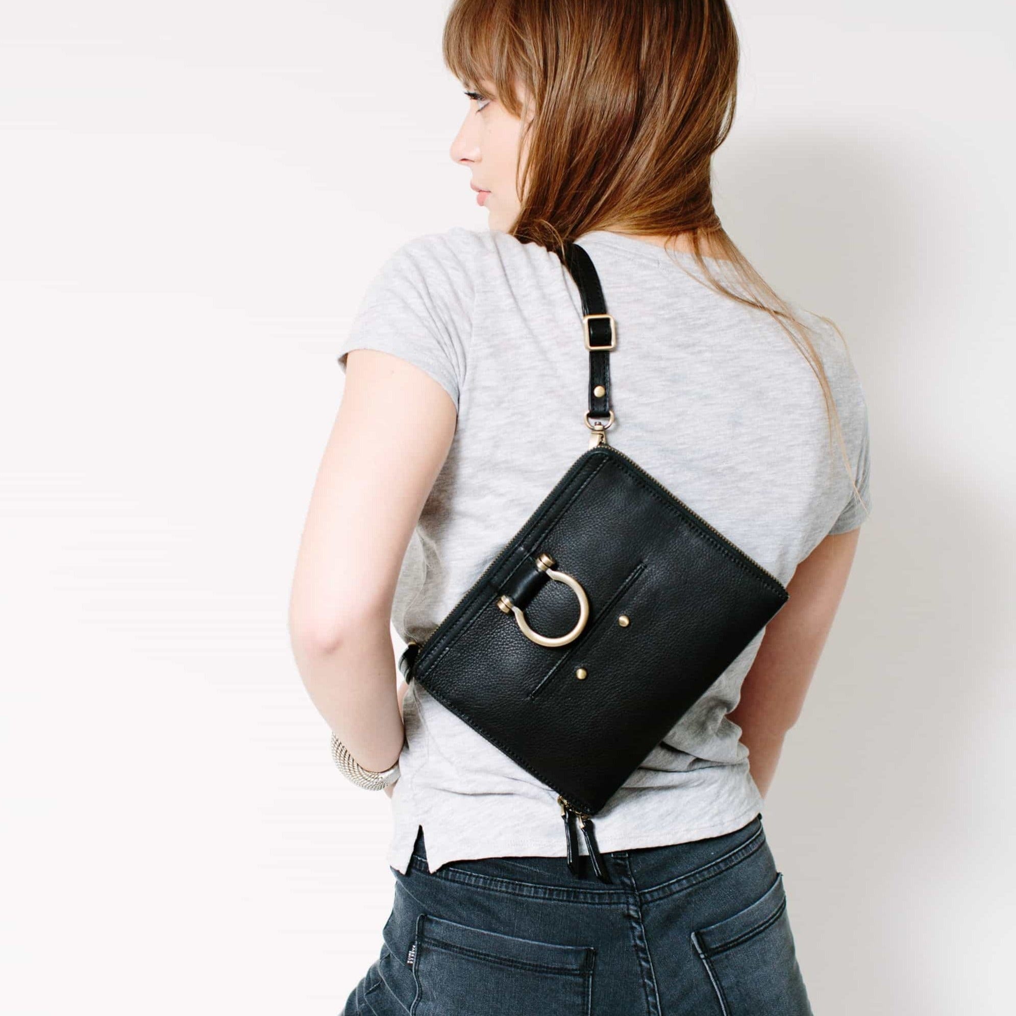 Wear the M mini crossbody bag in black raw leather over your shoulder to show off the Omega brass hardware.
