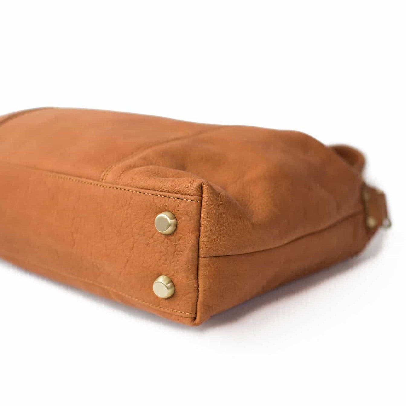 Linda Jean handbag in whisky tan raw leather has metal feet on the bottom to keep your bag protected.