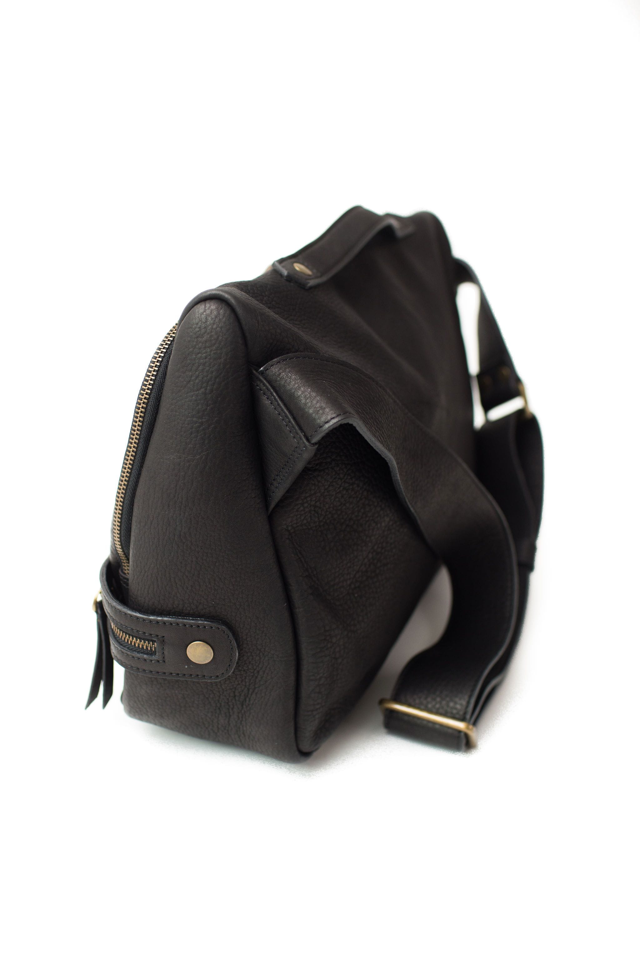 The Rapinoe unisex messenger bag in black raw leather has an adjustable strap and top handle.