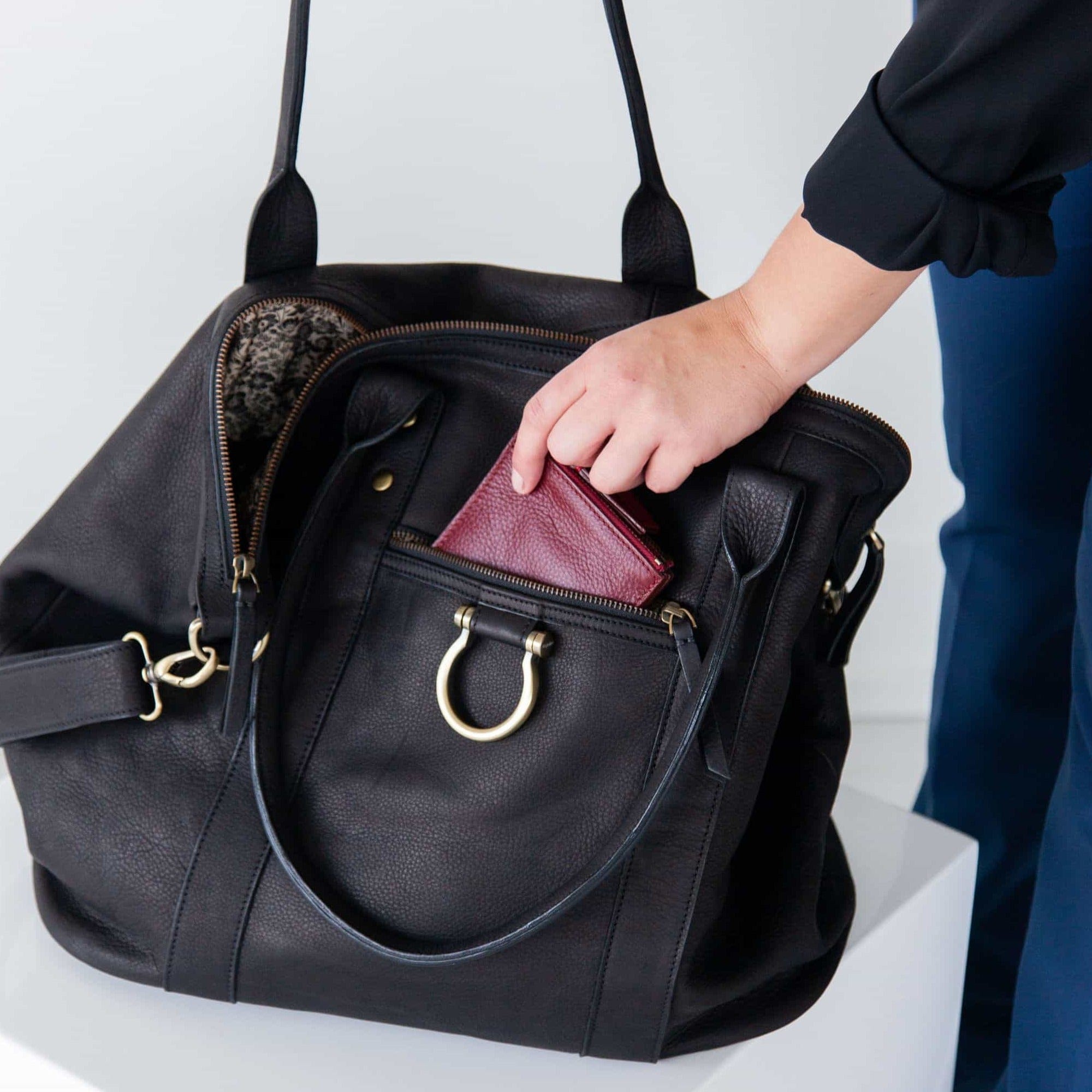 The So Honey weekender in black raw leather features an external zip pocket for quick-grab items.
